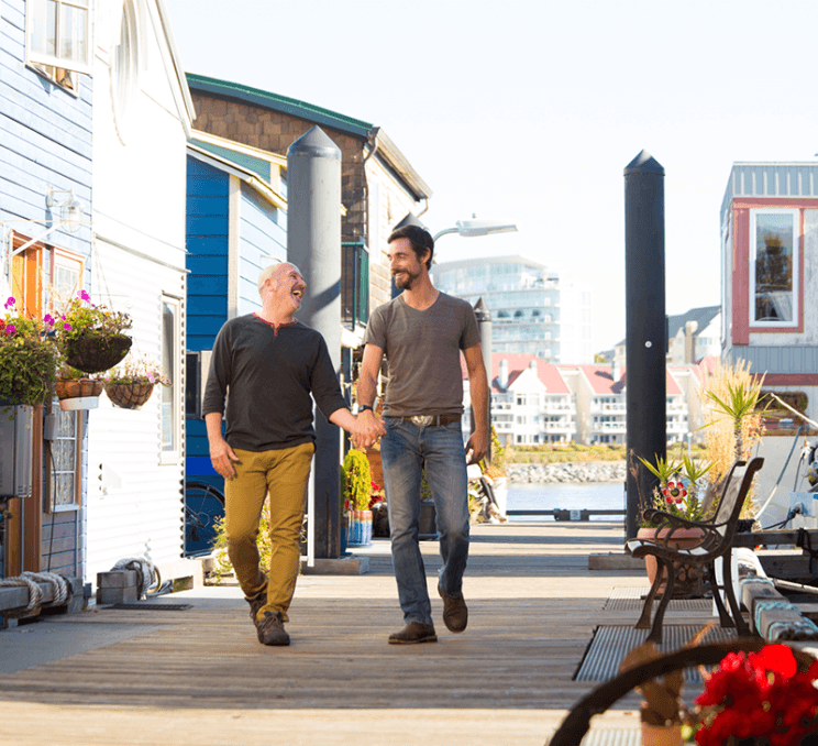 A couple walks hand-in-hand along Fisherman's Wharf in Victoria, BC