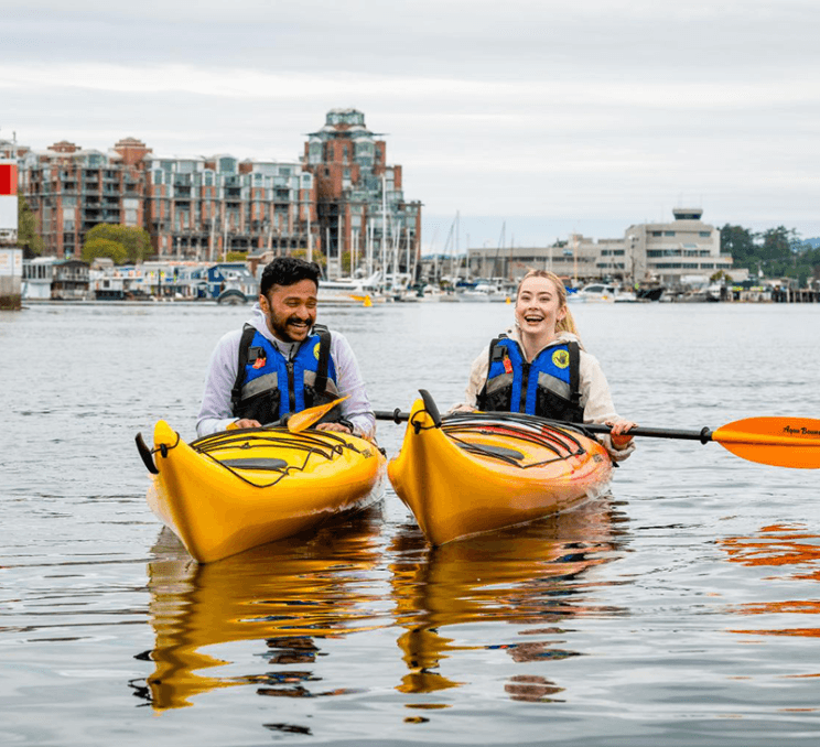 A couple of kayakers laugh on the waters of Victoria's Inner Harbour in Victoria, BC