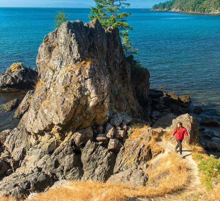 A woman explores a rock formation at East Sooke Park in Victoria, BC