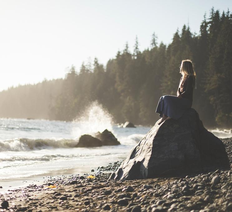 A woman sits atop a rock at Mystic Beach in Victoria, BC