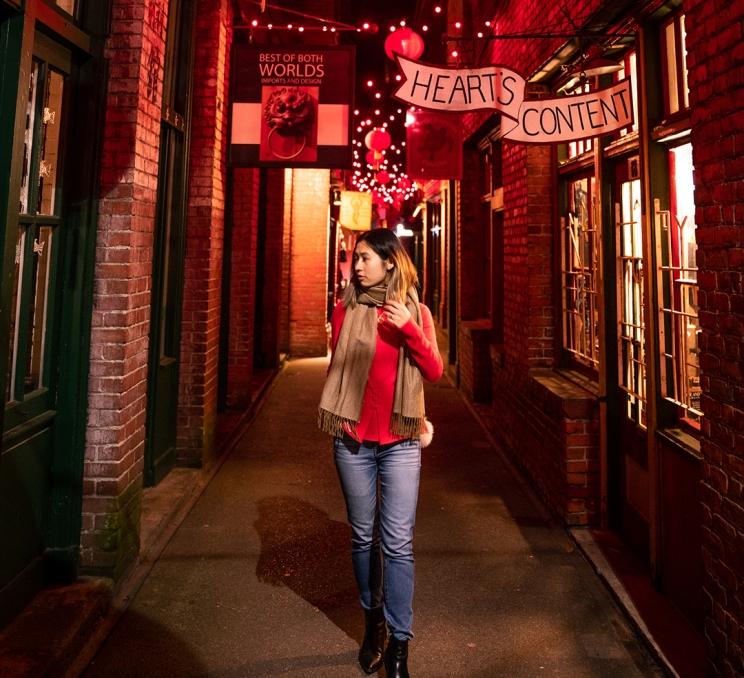 A woman walks through Fan Tan Alley in Chinatown at night in Victoria, BC