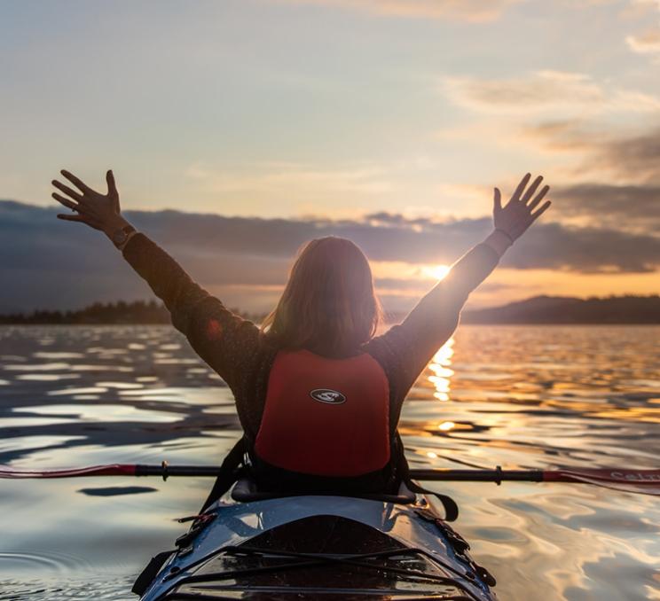 A woman enjoys the sunset while kayaking off the coast of Victoria, BC