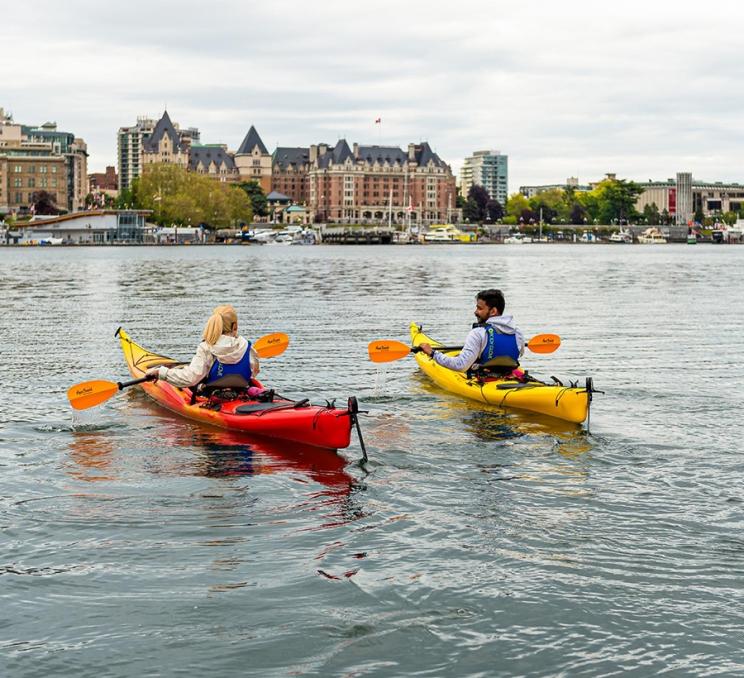 A pair of paddlers explore the Inner Harbour aboard kayaks in Victoria, BC