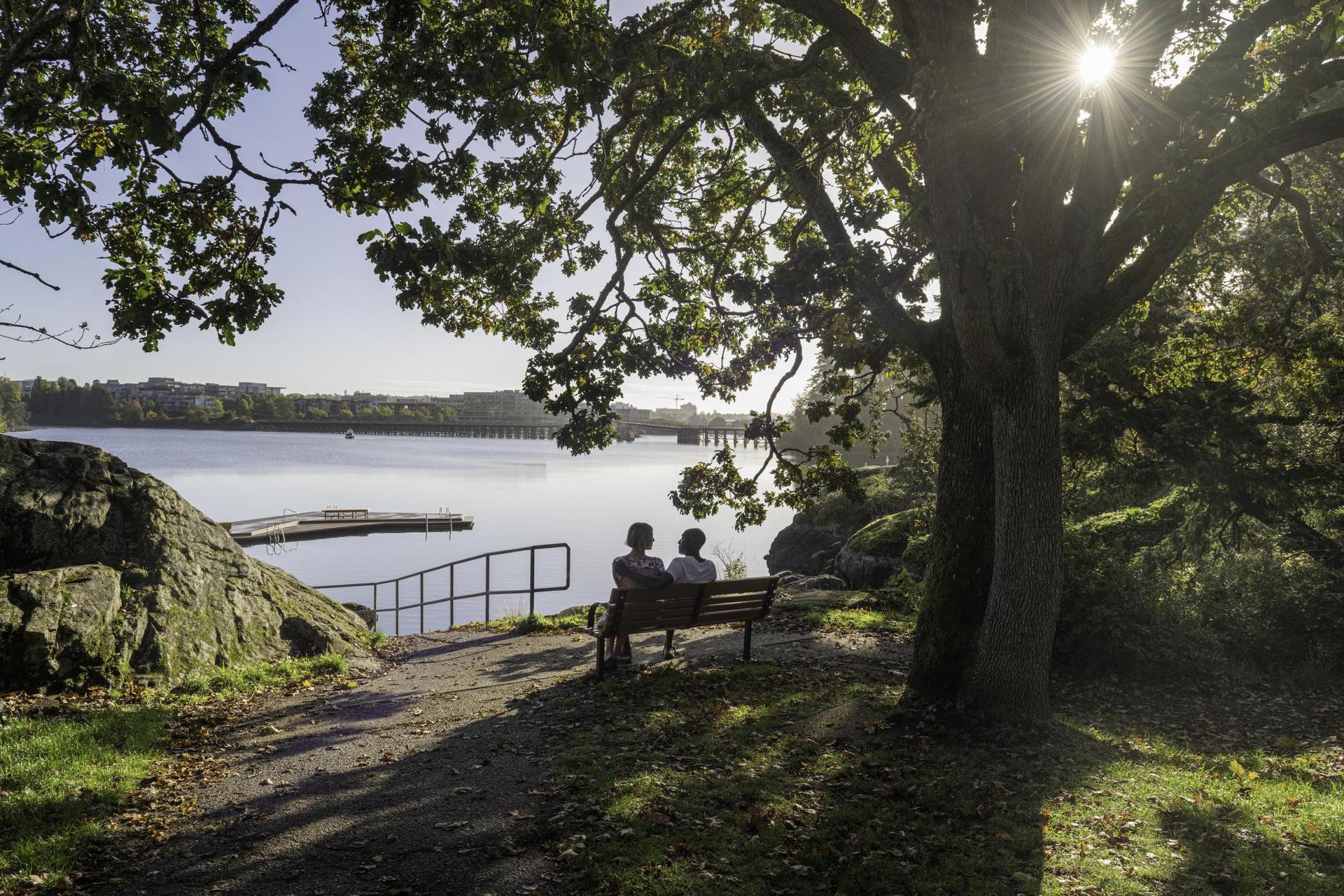 A couple sits on a park bench before taking a dip at Banfield Park along the Gorge Waterway in Victoria, BC