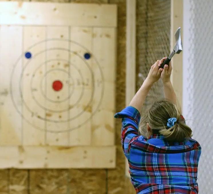 A woman partakes in axe throwing at Axe & Grind in Victoria, BC