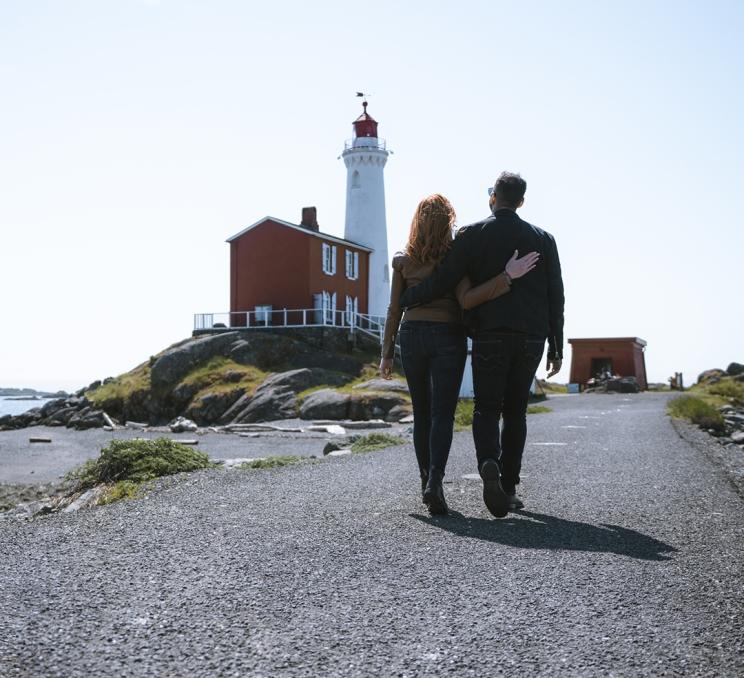 A couple walks towards Fisgard Lighthouse in Victoria, BC