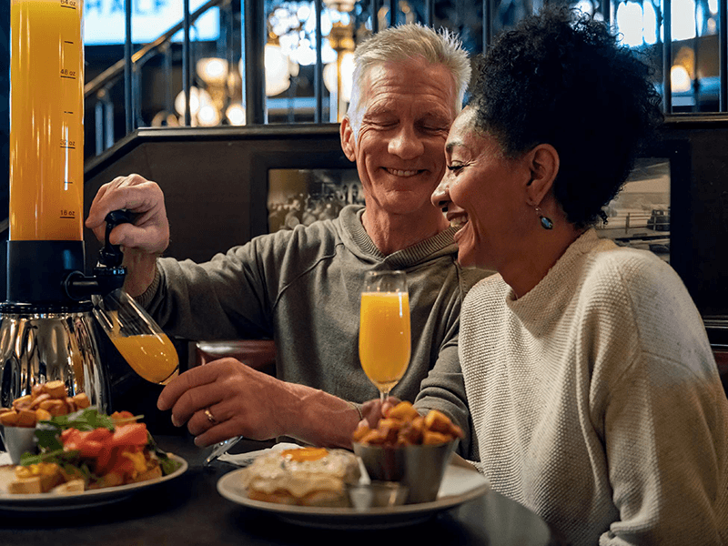 An older couple dines at the Bard and Banker with a Mimosa Tower