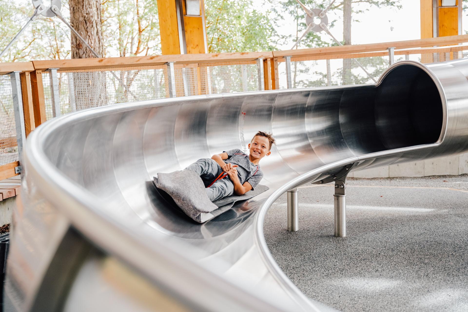 A boy sliding down the Malahat Skywalk's spiral slide at an undeniably quick pace!