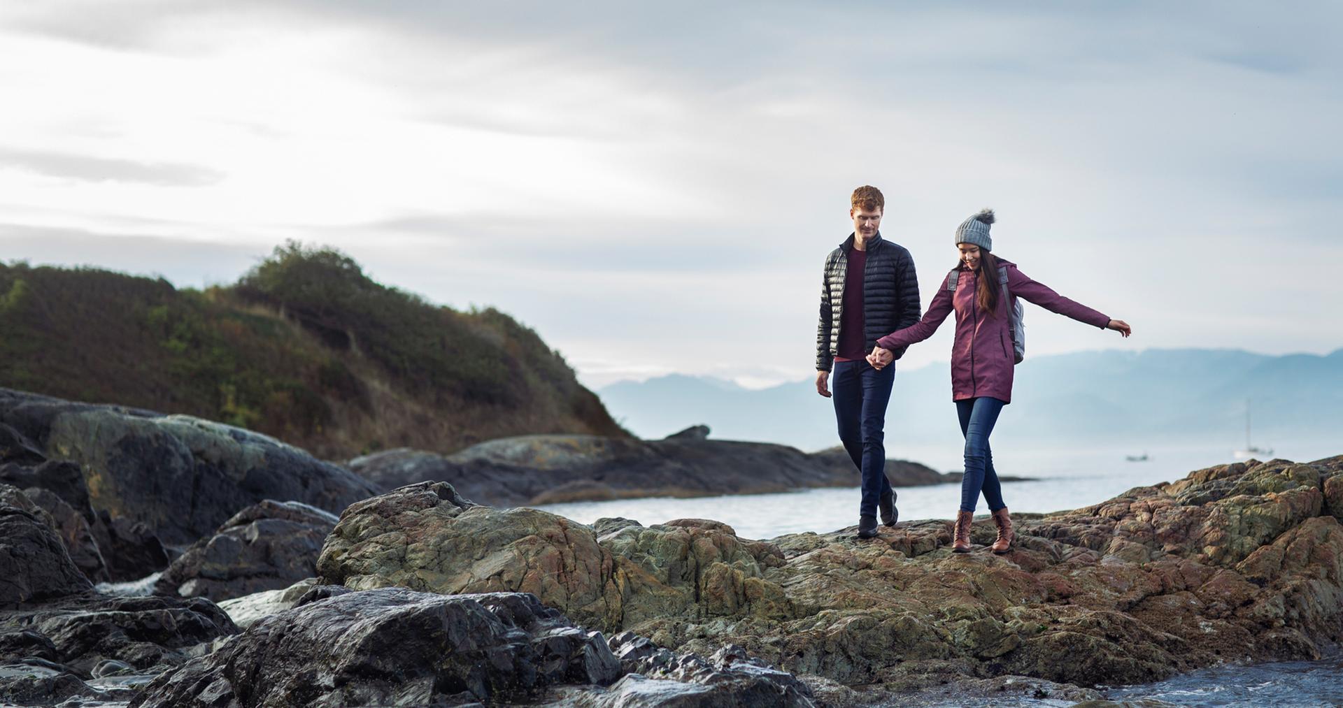 A young couple explores the beach along Dallas Road in the wintertime in Victoria, BC