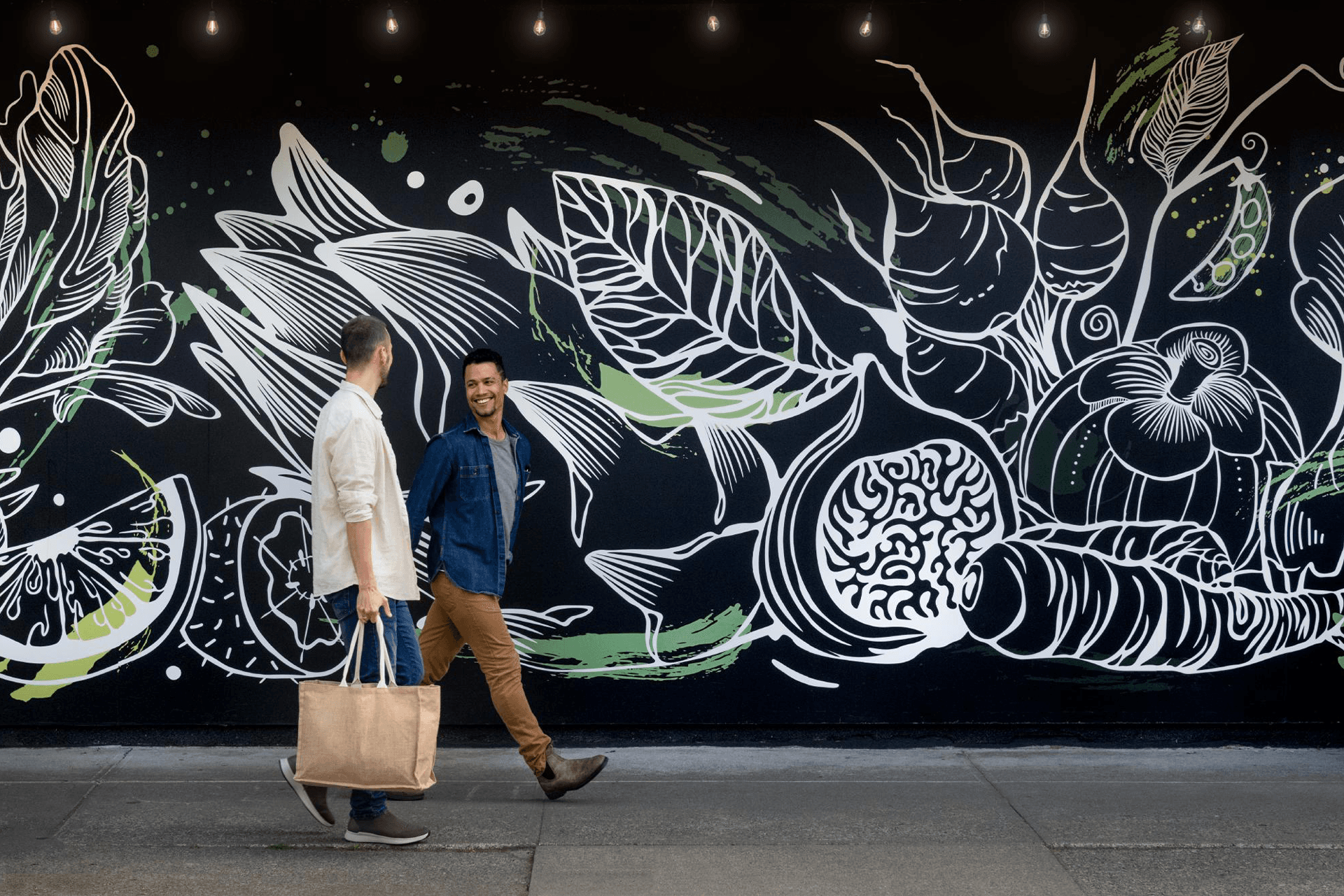 A couple explores Greater Victoria's vibrant shopping seen, backdropped by a local mural.