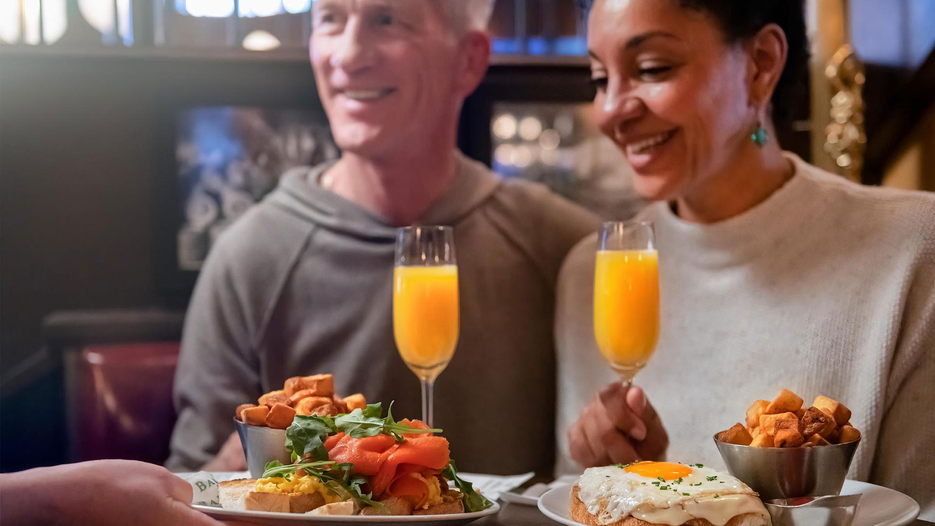 A couple sits down for brunch and mimosas at the Bard & Banker in Victoria, BC
