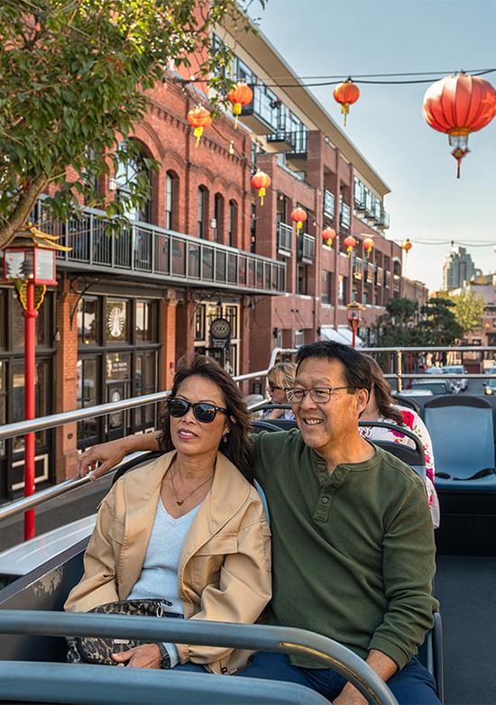 A couple tours Victoria's historic Chinatown aboard a hop-on bus