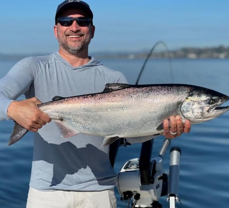 A man holds a salmon after a fishing charter trip in Victoria, BC