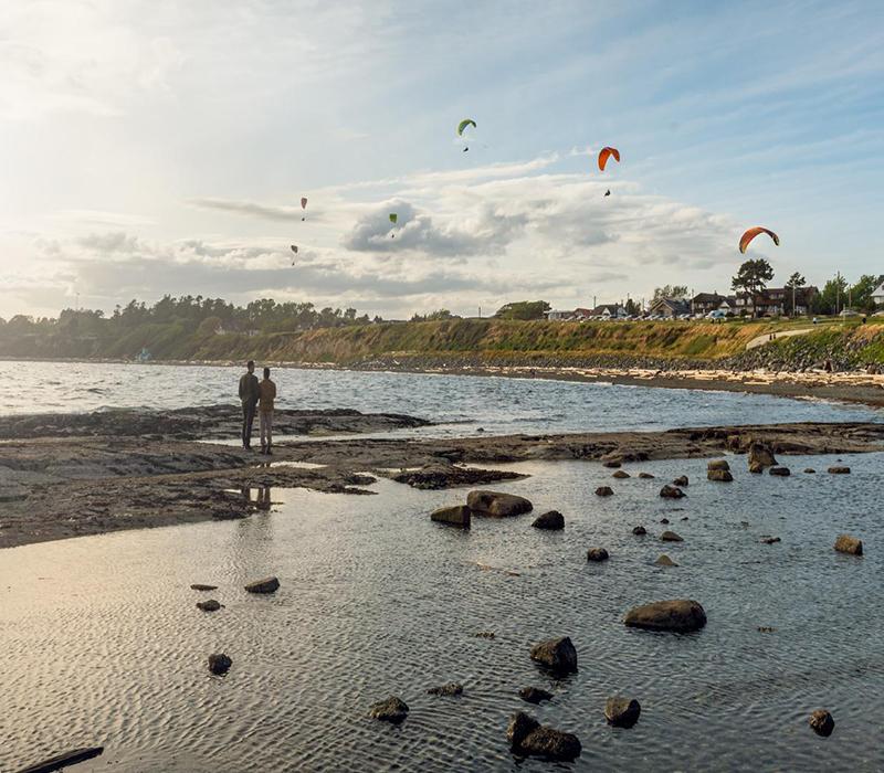 A couple watches the paragliders at Clover Point in Victoria, BC