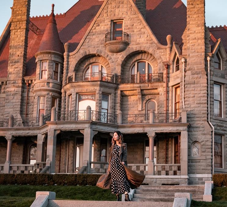 A woman stands outside of Craigdarroch Castle in Victoria, BC