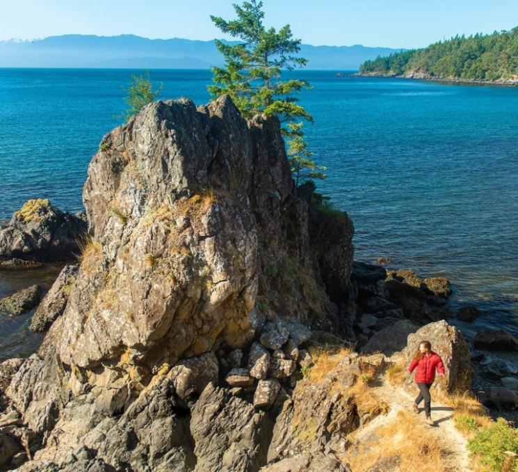 A woman explores the coastline at East Sooke Regional Park in Victoria, BC