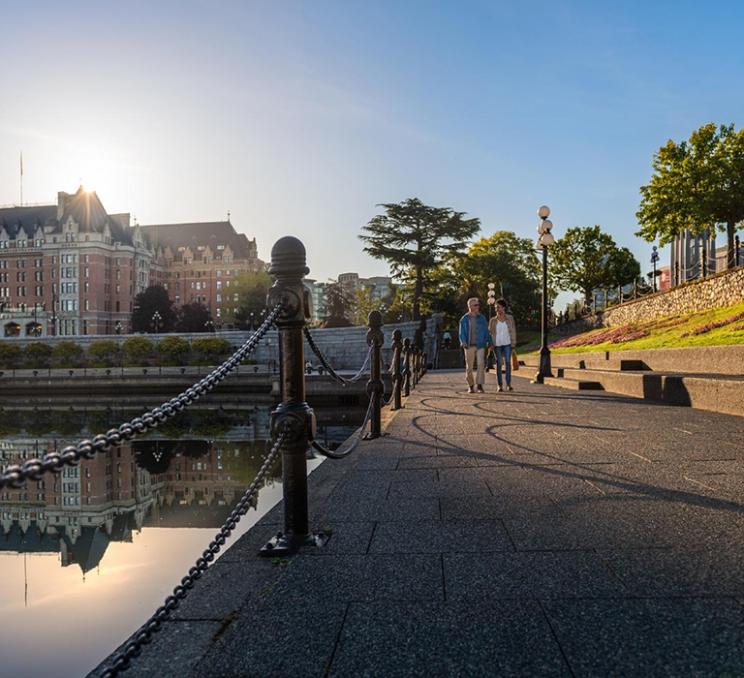 A couple walks along Victoria's iconic Inner Harbour