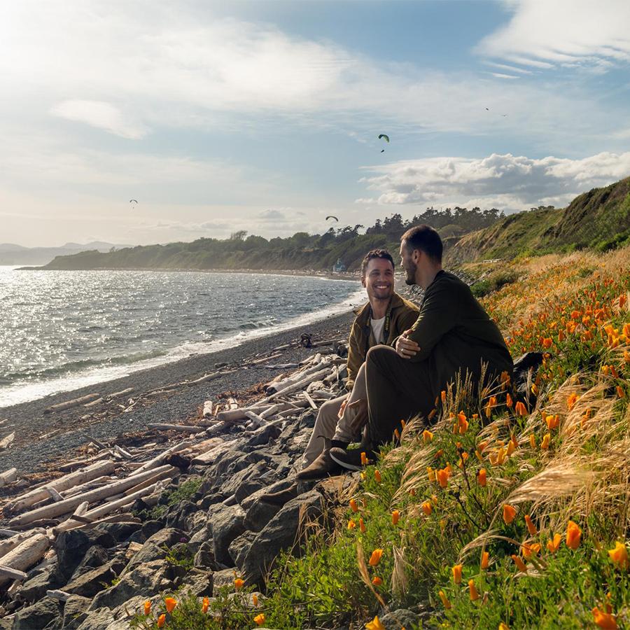 A couple sits along a beach in Greater Victoria, BC