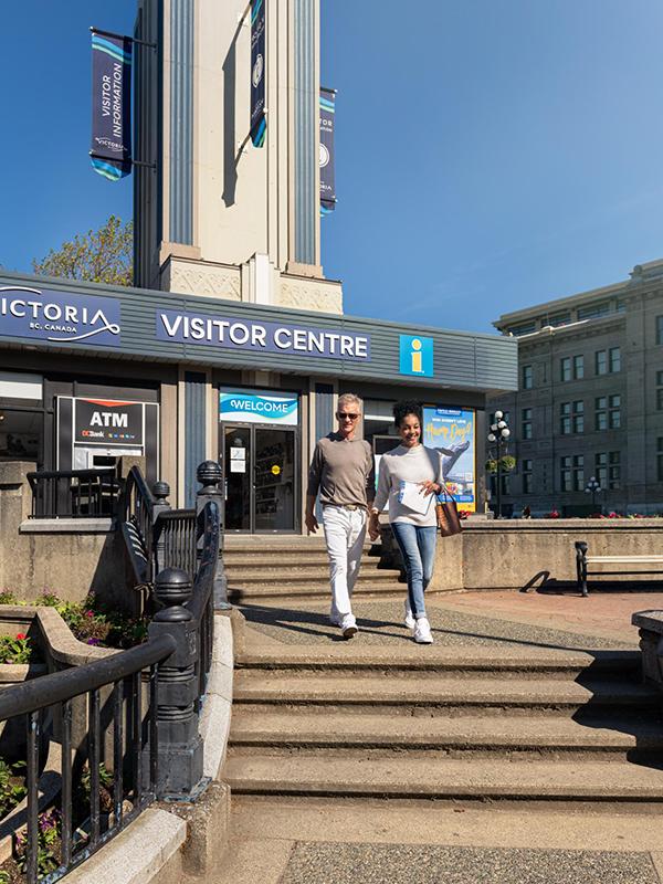 A couple walks outside the Victoria Visitor Centre in Victoria, BC