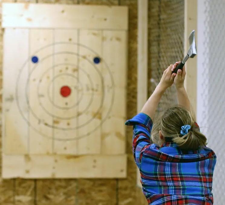 A woman throws an axe at Axe & Grind axe throwing in Victoria, BC