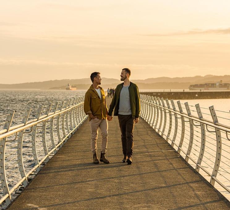 A couple walks along the Ogden Point Breakwater in Victoria, BC