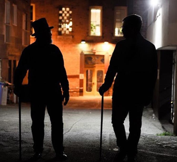 A tour guide walks through a dark alley on a Ghostly Walks tour in Victoria, BC