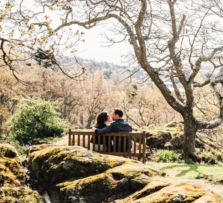 A couple sits beneath a Gary Oak tree at Government House in Victoria, BC