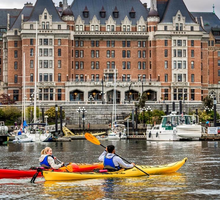 Kayakers paddle past the Fairmont Empress on Victoria, BC's Inner Harbour