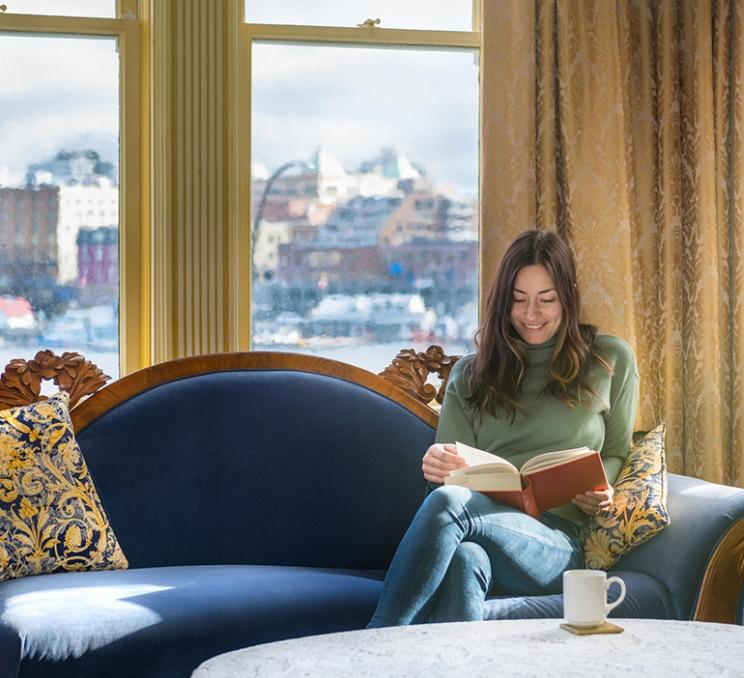 A woman enjoys a coffee and a book in the Pendray Inn in Victoria, BC