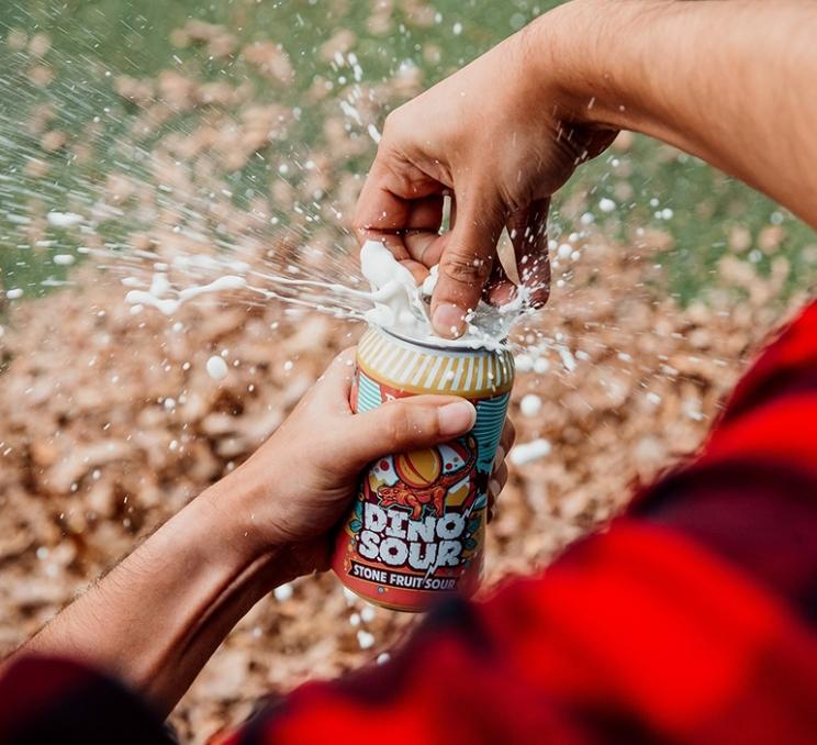 A man cracks open a Dino Sour from Phillips Brewing in Victoria, BC