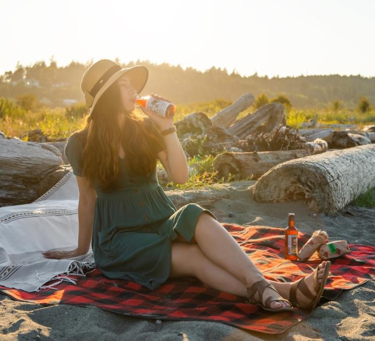 A woman enjoys a soda on a beach in Greater Victoria, BC