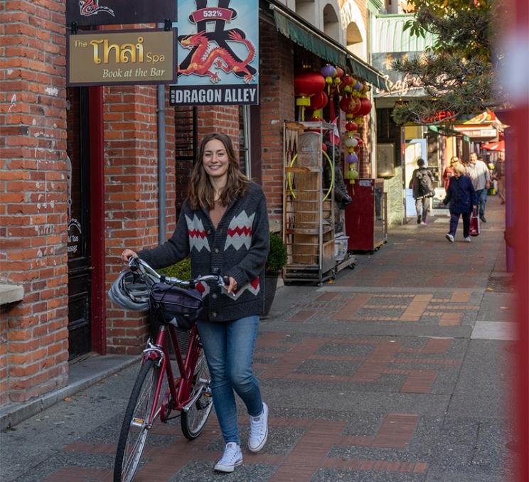 A woman pushes her rental bike through Chinatown in Victoria, BC