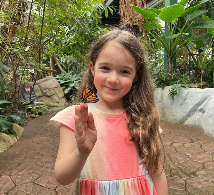 A young girl holds a butterfly at the Victoria Butterfly Gardens in Victoria, BC