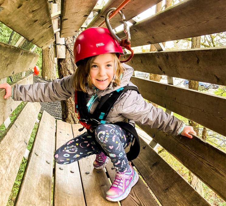 A young girl crawls through a tube at WildPlay Elements Park in Victoria, BC