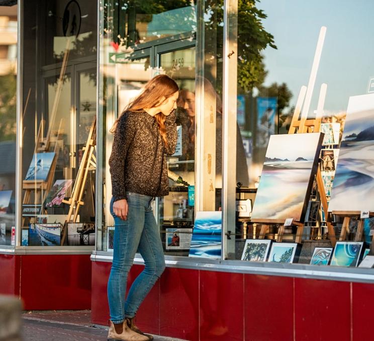 A woman window shops outside an art store in Victoria, BC