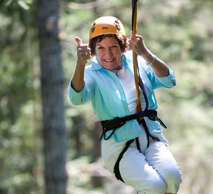 A woman zips through the tree canopy on a zipline at Adrena LINE Zipline Adventure Tours in Victoria, BC