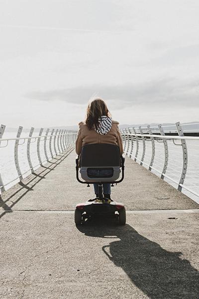 A person with a disability rides a mobility scooter down the breakwater in Victoria, BC