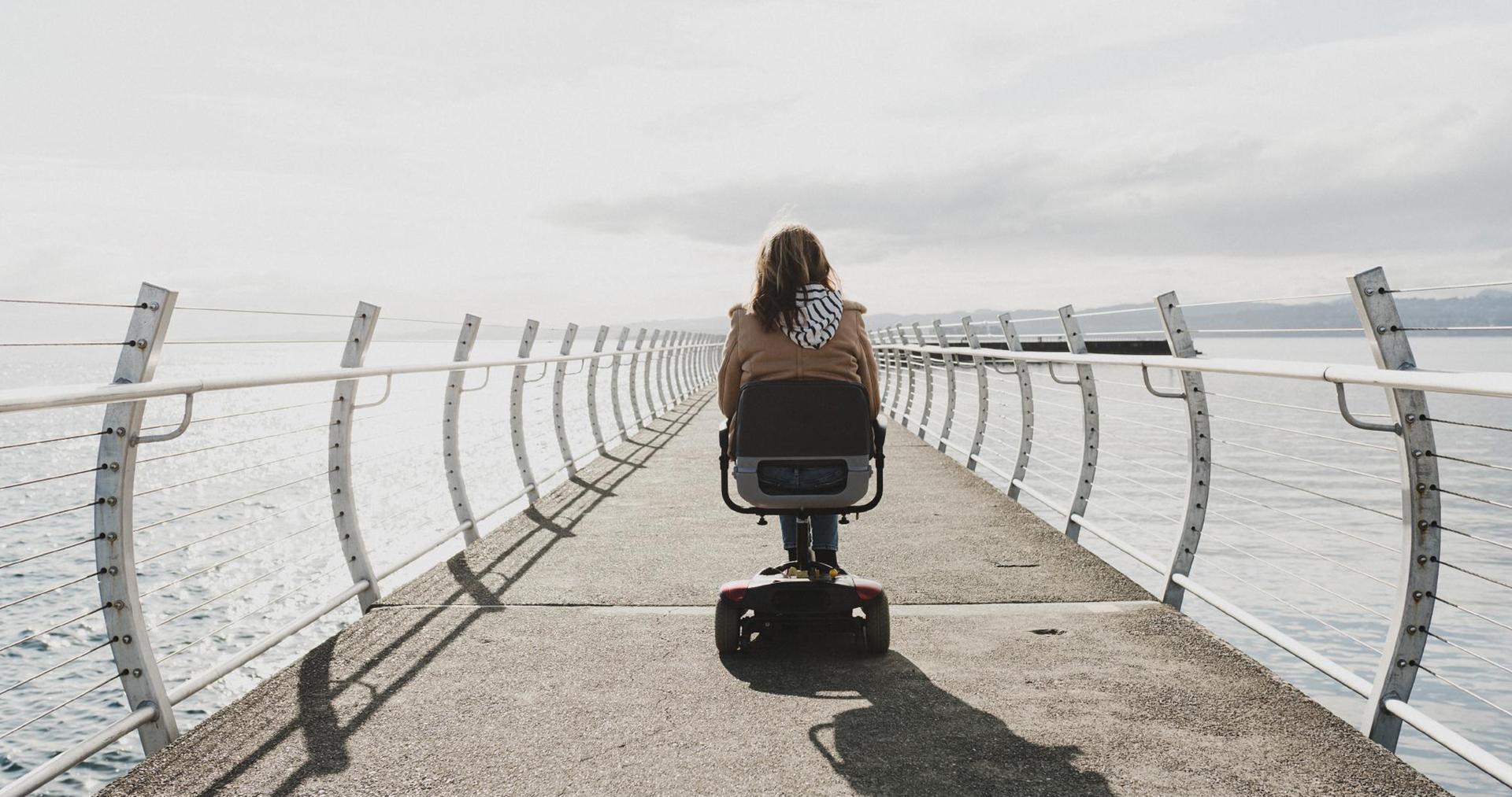 A person with a disability rides a mobility scooter along the breakwater in Victoria, BC