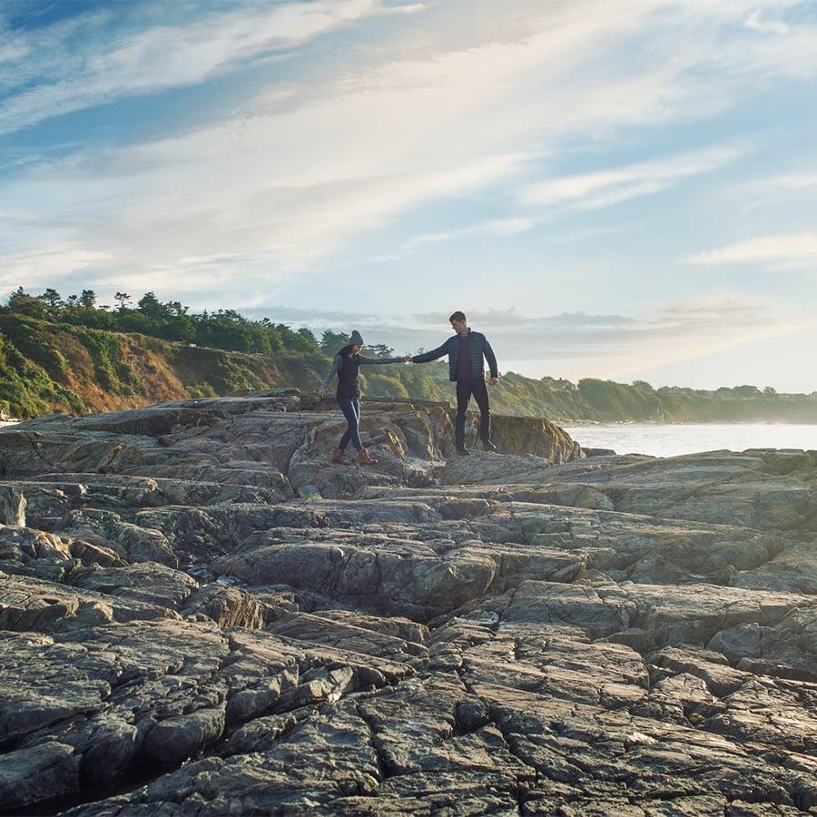 A couple explores the beach along Dallas Road hand-in-hand in Victoria, BC