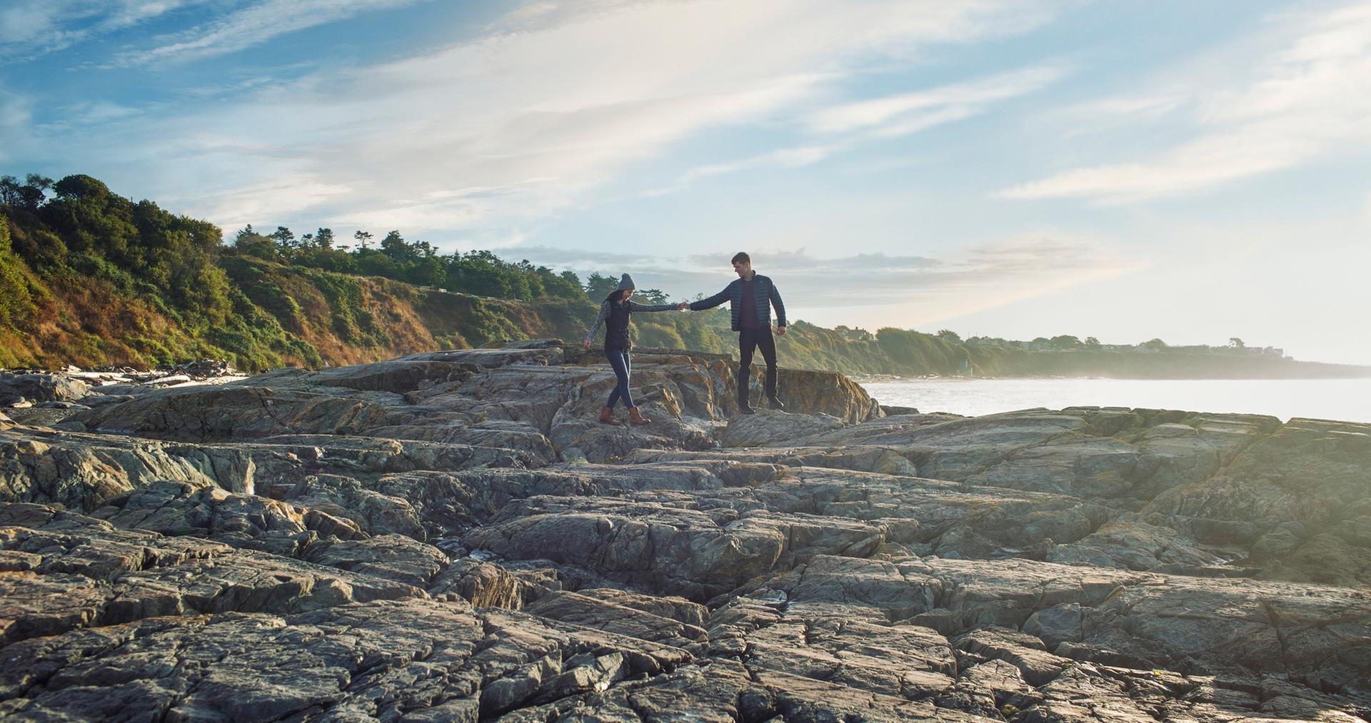 A couple walks along the rocks at Dallas Road Beach in Victoria, BC