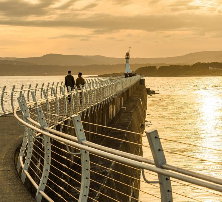 A couple takes a sunset walk along the Ogden Point Breakwater in Victoria, BC