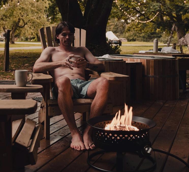 A man rests next to a firepit at Wildwood Saunas in Victoria, BC