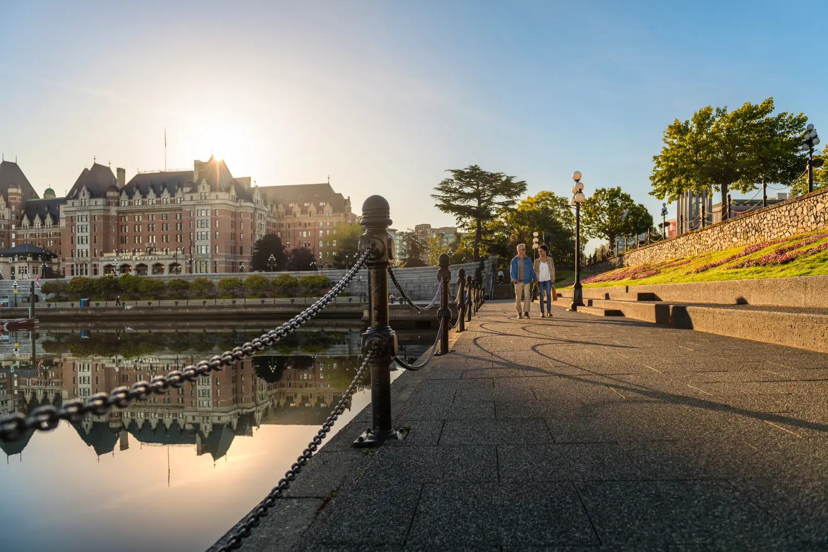 A couple walking along Victoria's Inner Harbour