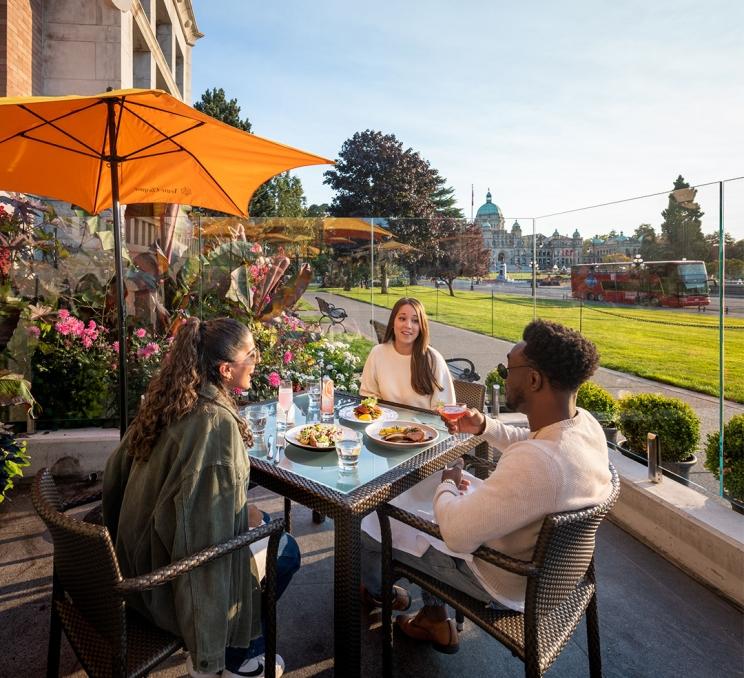 A group of friends dine on the patio at Q at the Empress, a restaurant at the Fairmont Empress, steps from the Iconic Inner Harbour in Victoria, BC