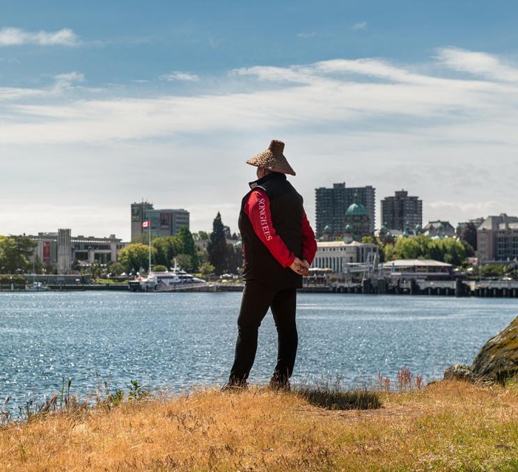 An Indigenous guide from Explore Songhees looks out over Victoria, BC's Inner Harbour