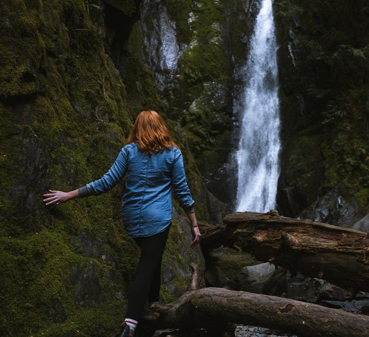 A woman in a denim top brushes the moss near Niagara Falls in Victoria, BC