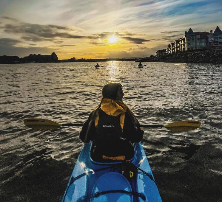 A kayaker paddles on the Inner Harbour at sunset in Victoria, BC